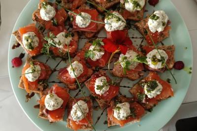 Plateau en bois avec verrines garnies, bol de pain tranché et bouteille de vin mousseux en arrière-plan.