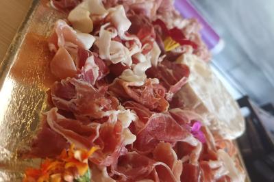 Plateau en bois avec verrines garnies, bol de pain tranché et bouteille de vin mousseux en arrière-plan.