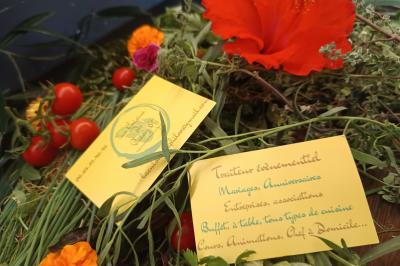 Plateau en bois avec verrines garnies, bol de pain tranché et bouteille de vin mousseux en arrière-plan.