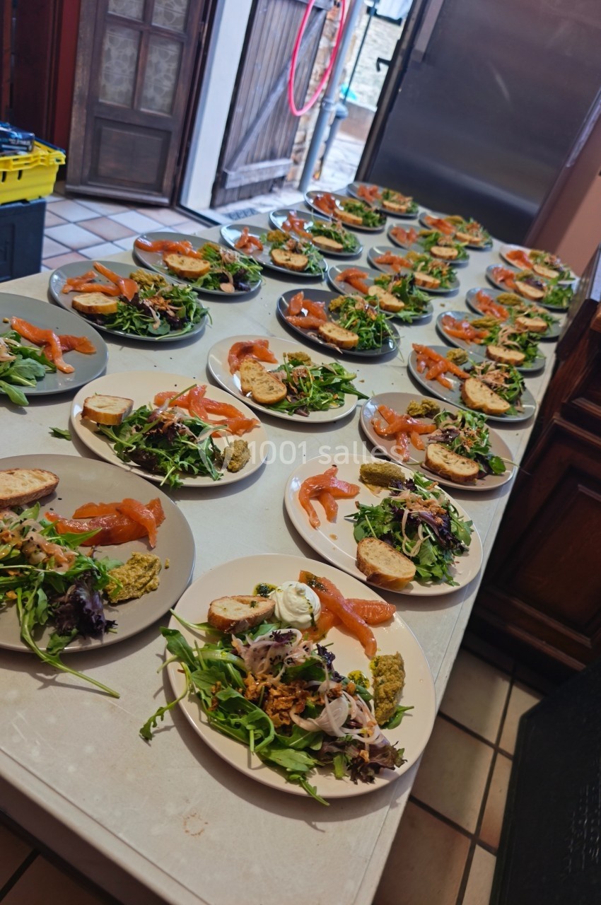 Assiettes dressées avec des entrées composées de saumon fumé, salade verte, pain et garnitures variées sur une table.