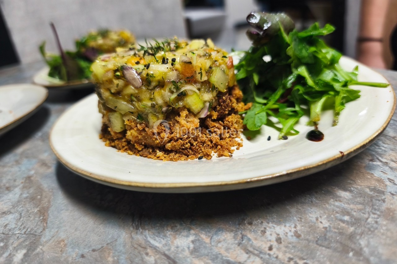 Plat dressé avec un crumble salé, une garniture de légumes et herbes fraîches, accompagné de salade verte.