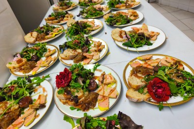 Assiettes garnies de foie gras, salade verte, figues et pain, disposées sur une table dans une cuisine.