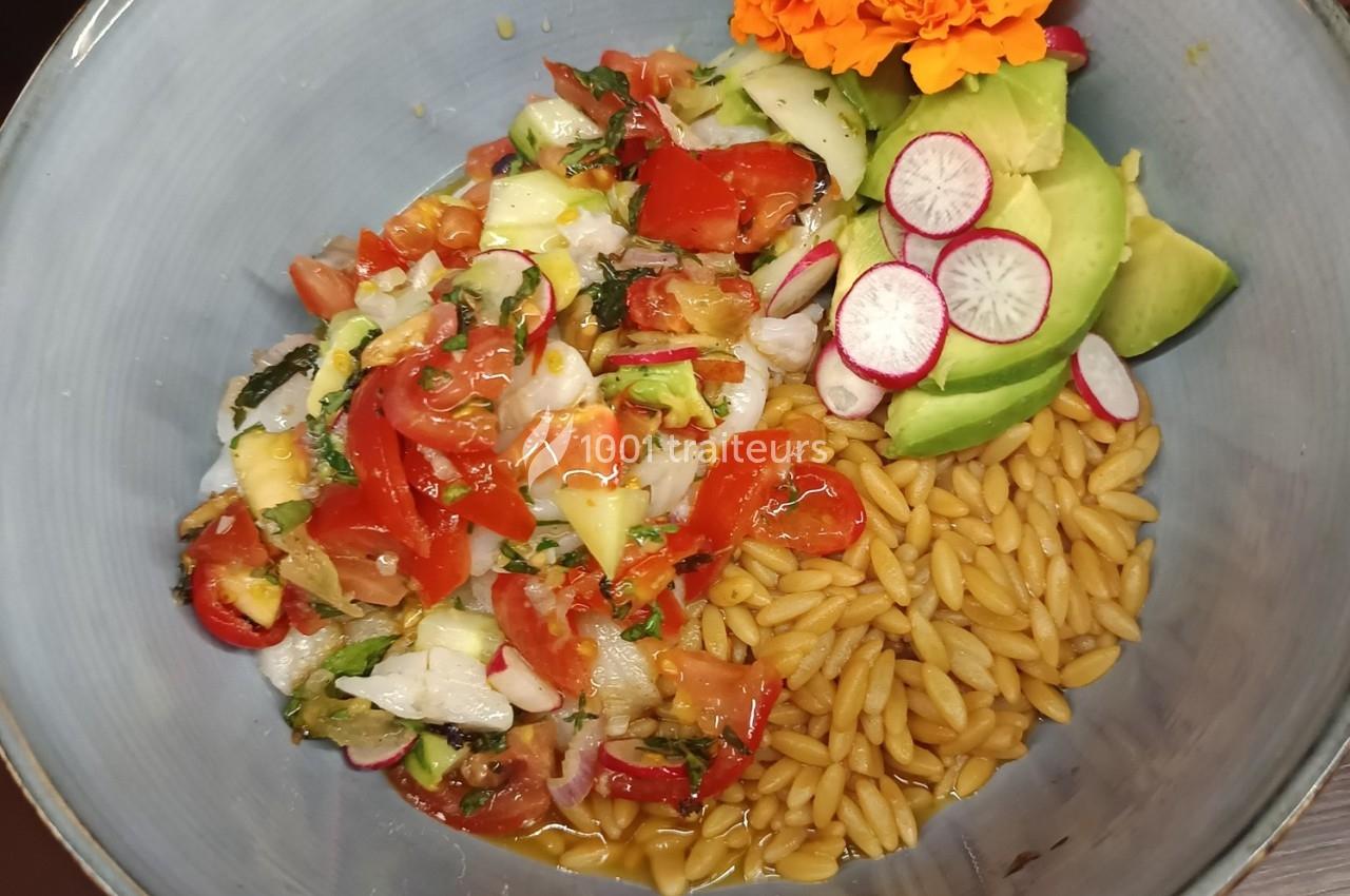 Assiette composée de ceviche de poisson, orzo, tranches d'avocat, radis et fleurs comestibles en décoration.