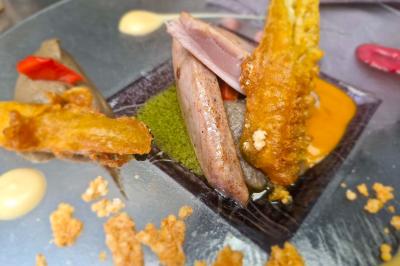 Plat gastronomique composé de viande, légumes, champignons, sauce caramélisée et croustillant sur une assiette décorative.