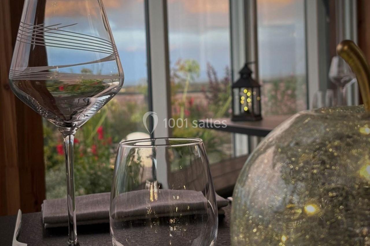 Deux verres posés sur une table élégante avec vue sur un paysage au coucher du soleil et une lanterne en arrière-plan.