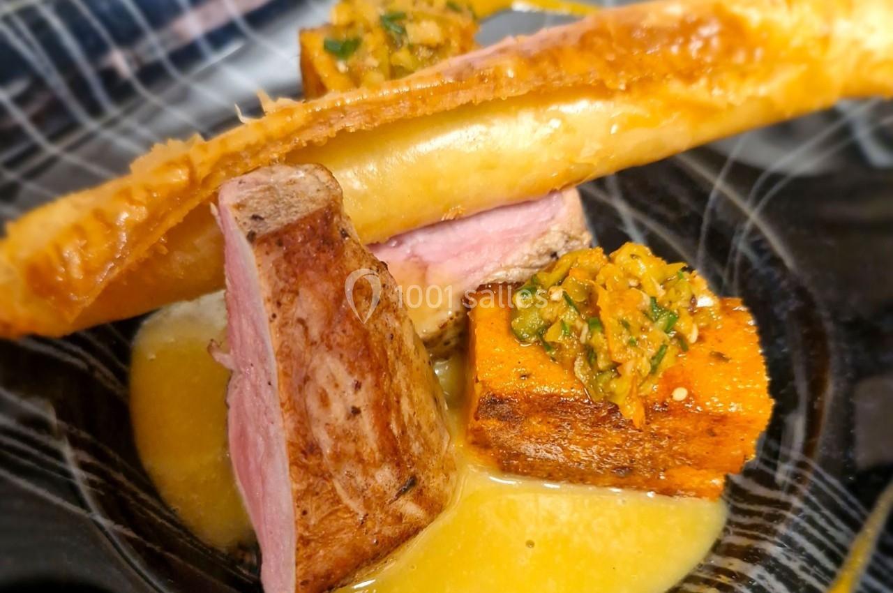 Assiette gastronomique avec viande rosée, cubes de légumes, sauce jaune et croustillant doré en décoration.