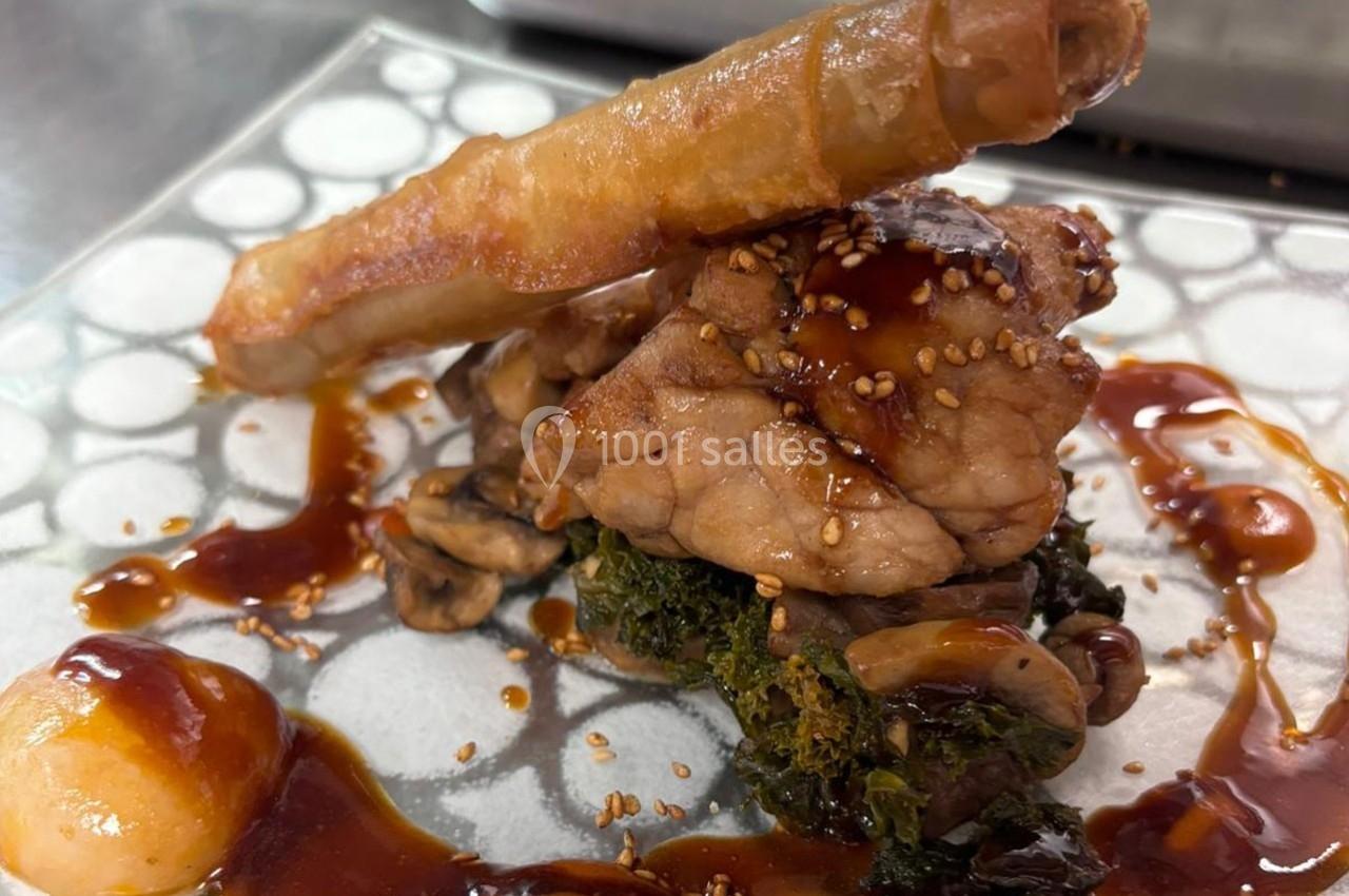 Plat gastronomique composé de viande, légumes, champignons, sauce caramélisée et croustillant sur une assiette décorative.