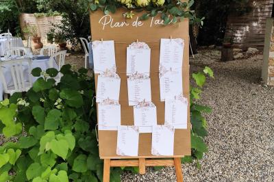 Salle de réception avec tables rondes dressées, nappes blanches, chemins de table en dentelle et décoration élégante.