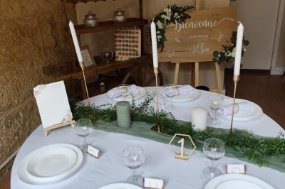 Salle de réception décorée avec des tables rondes dressées, nappes blanches et chaises ornées de nœuds beige.