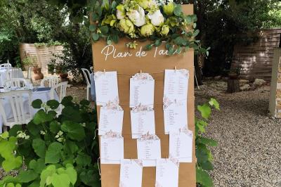 Salle de réception décorée avec des tables rondes dressées, nappes blanches et chaises ornées de nœuds beige.