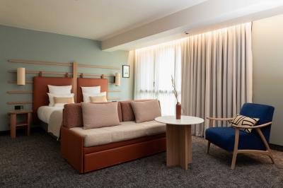 Salle à manger lumineuse avec une grande table en bois, des chaises en rotin et des étagères décoratives en arrière-plan.