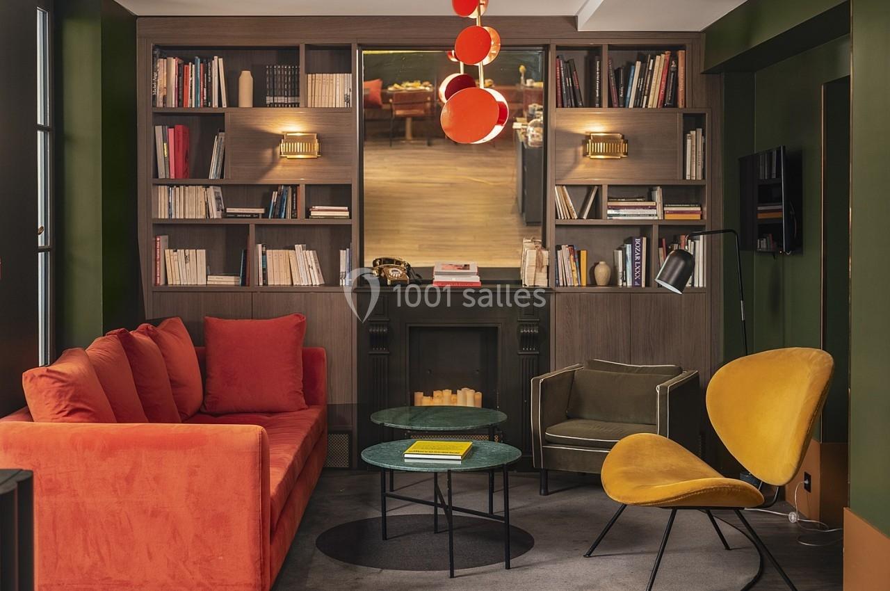 Salon avec canapé rouge, fauteuils jaunes, bibliothèque intégrée, table basse et cheminée décorative.