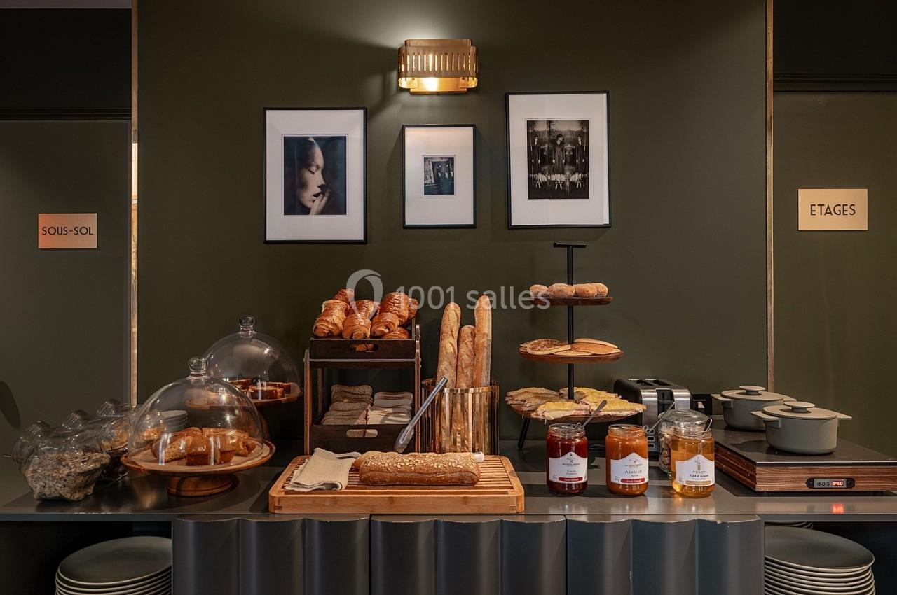 Buffet de petit-déjeuner avec pains, viennoiseries, confitures, et plats chauds sur un comptoir dans un décor élégant.