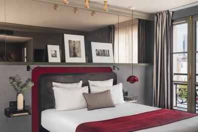 Chambre d'hôtel moderne avec lit double, décoration élégante, photos encadrées et vue sur une salle de bain attenante.