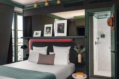 Chambre d'hôtel moderne avec lit double, décoration élégante, photos encadrées et vue sur une salle de bain attenante.