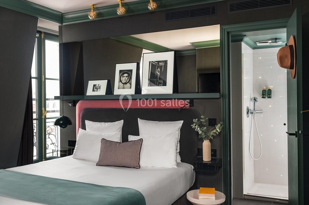 Chambre d'hôtel moderne avec lit double, décoration élégante, photos encadrées et vue sur une salle de bain attenante.