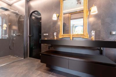 Salle de bain moderne avec carrelage marron, baignoire, fenêtre lumineuse, sèche-serviettes blanc et meuble en bois.