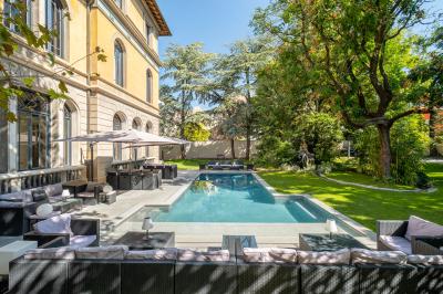 Chambre lumineuse avec lit double, bureau, poutres apparentes et murs verts, décorée avec des tableaux.
