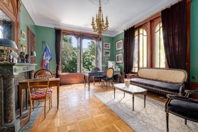 Chambre lumineuse avec lit double, bureau, poutres apparentes et murs verts, décorée avec des tableaux.