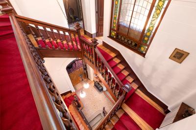 Chambre lumineuse avec lit double, bureau, poutres apparentes et murs verts, décorée avec des tableaux.