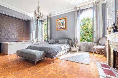 Chambre lumineuse avec lit double, bureau, poutres apparentes et murs verts, décorée avec des tableaux.