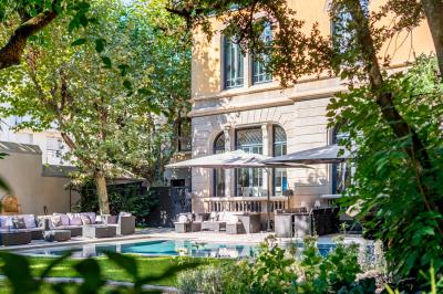 Chambre lumineuse avec lit double, bureau, poutres apparentes et murs verts, décorée avec des tableaux.