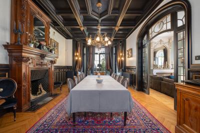 Chambre lumineuse avec lit double, bureau, poutres apparentes et murs verts, décorée avec des tableaux.