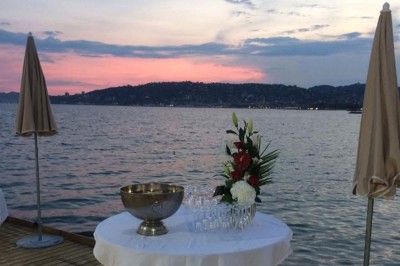 Plateau en bois avec verrines garnies de crevettes, tomates, olives et herbes fraîches, disposées sur une nappe beige.