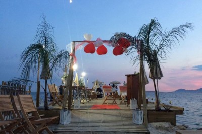 Plateau en bois avec verrines garnies de crevettes, tomates, olives et herbes fraîches, disposées sur une nappe beige.
