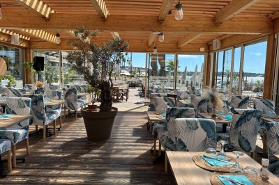 Plateau en bois avec verrines garnies de crevettes, tomates, olives et herbes fraîches, disposées sur une nappe beige.