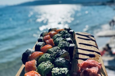 Plateau en bois avec verrines garnies de crevettes, tomates, olives et herbes fraîches, disposées sur une nappe beige.
