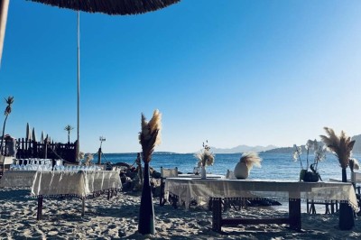 Plateau en bois avec verrines garnies de crevettes, tomates, olives et herbes fraîches, disposées sur une nappe beige.