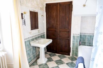 Trampoline rond avec filet de sécurité installé dans un jardin verdoyant, près d'une maison en pierre.