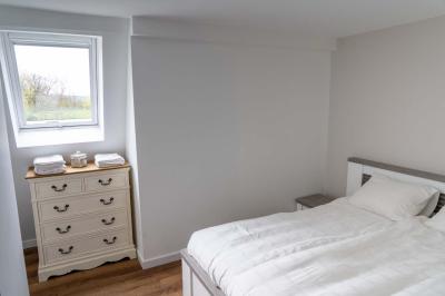 Trampoline rond avec filet de sécurité installé dans un jardin verdoyant, près d'une maison en pierre.