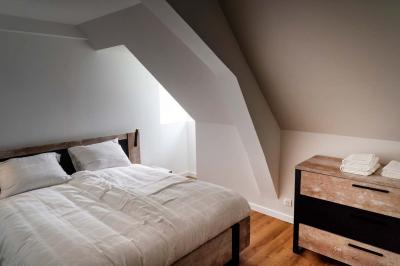 Trampoline rond avec filet de sécurité installé dans un jardin verdoyant, près d'une maison en pierre.