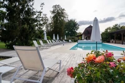 Trampoline rond avec filet de sécurité installé dans un jardin verdoyant, près d'une maison en pierre.