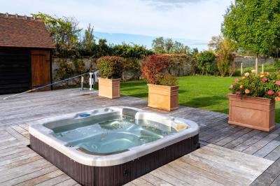 Trampoline rond avec filet de sécurité installé dans un jardin verdoyant, près d'une maison en pierre.