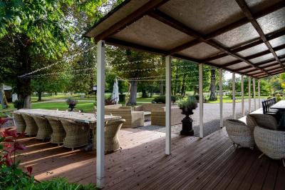 Trampoline rond avec filet de sécurité installé dans un jardin verdoyant, près d'une maison en pierre.
