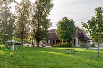 Trampoline rond avec filet de sécurité installé dans un jardin verdoyant, près d'une maison en pierre.