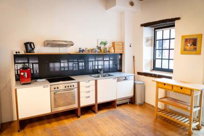 Trampoline rond avec filet de sécurité installé dans un jardin verdoyant, près d'une maison en pierre.