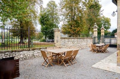 Trampoline rond avec filet de sécurité installé dans un jardin verdoyant, près d'une maison en pierre.