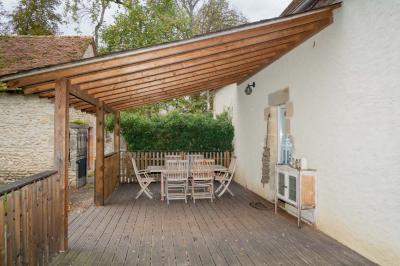 Trampoline rond avec filet de sécurité installé dans un jardin verdoyant, près d'une maison en pierre.