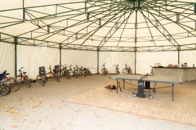 Trampoline rond avec filet de sécurité installé dans un jardin verdoyant, près d'une maison en pierre.