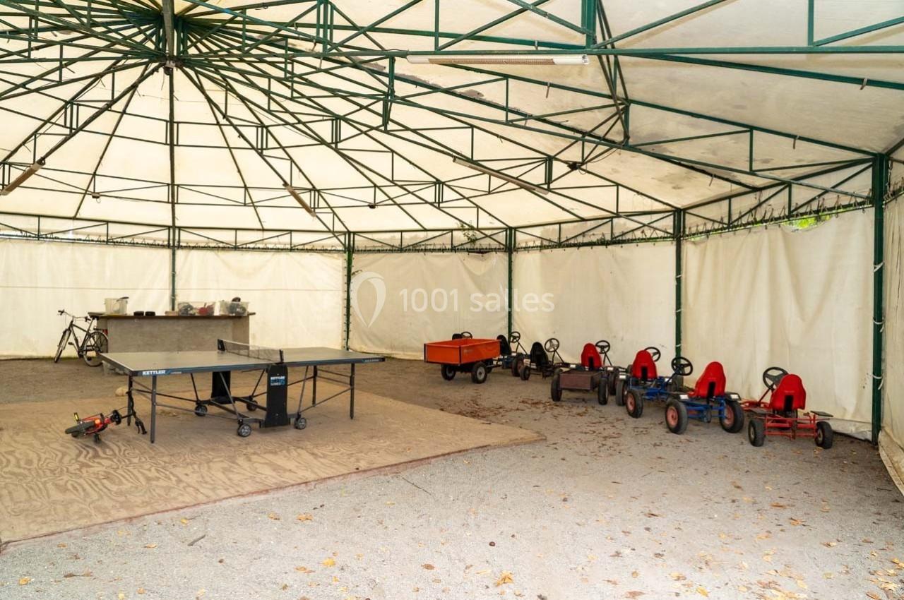 Espace couvert avec des karts à pédales alignés, une table de ping-pong et un comptoir en arrière-plan.