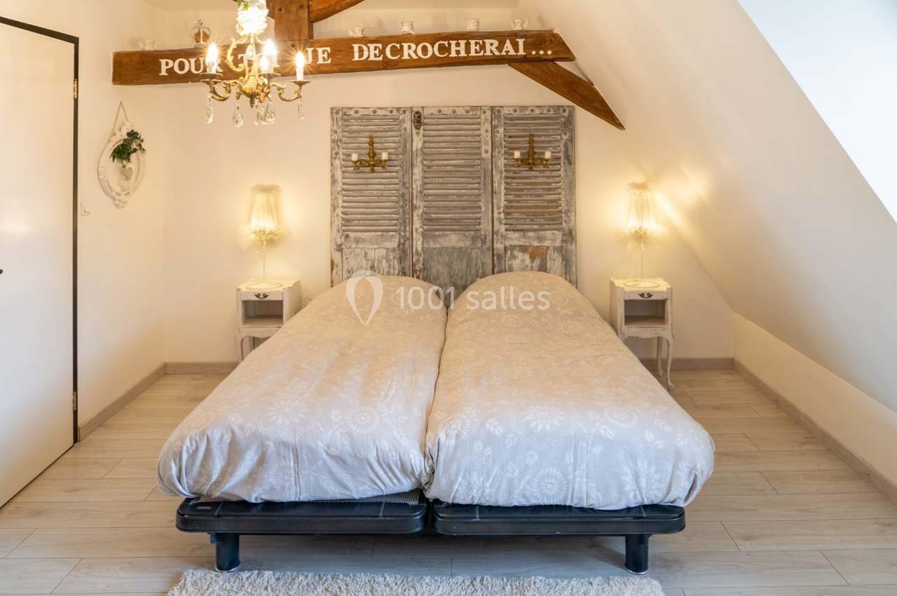 Deux lits simples côte à côte dans une chambre mansardée avec poutres apparentes et décoration rustique.