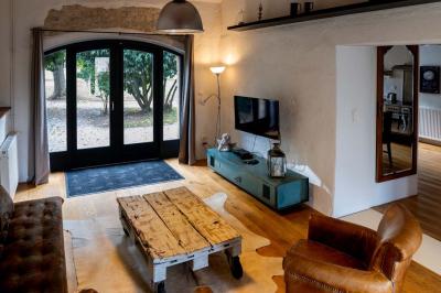 Trampoline rond avec filet de sécurité installé dans un jardin verdoyant, près d'une maison en pierre.