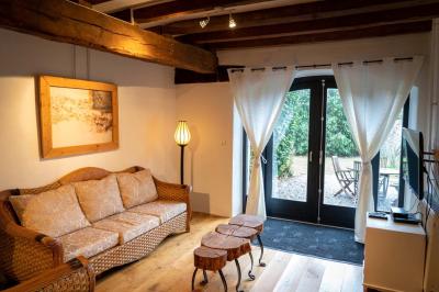 Trampoline rond avec filet de sécurité installé dans un jardin verdoyant, près d'une maison en pierre.