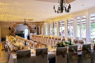 Trampoline rond avec filet de sécurité installé dans un jardin verdoyant, près d'une maison en pierre.