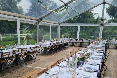 Trampoline rond avec filet de sécurité installé dans un jardin verdoyant, près d'une maison en pierre.