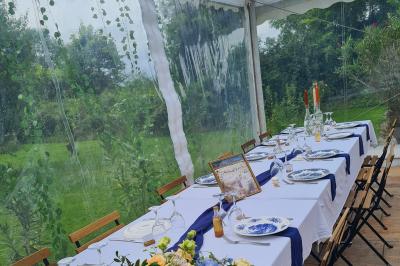 Trampoline rond avec filet de sécurité installé dans un jardin verdoyant, près d'une maison en pierre.